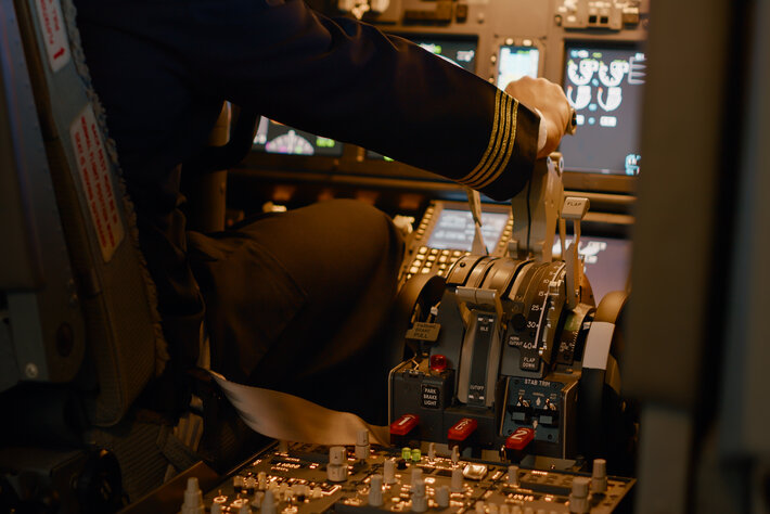 Aviation crew flying airplane with engine lever to throttle, using dashboard command buttons to takeoff. Control panel navigantion and windscreen to fly plane, using power handle. Close up.
