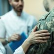 Close up of army soldier being consoled while talking with doctors at clinic
