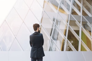 Rear view of businessman standing in front of modern corporate building