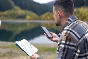 A young man with a map in his hands against the backdrop of mountains