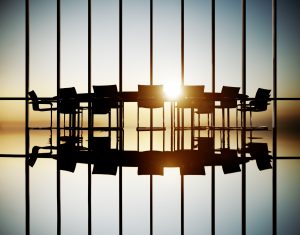 An office with a big chair and multiple chairs facing a sunset