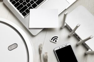 technological devices, which includes a wi-fi router, mobile phone, laptop and an wireless automatic vacuum cleaner, that is placed on a white background.