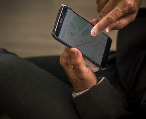 A man holding a phone with a location app shown on the phone