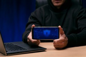 A man holding a phone with a security logo on it